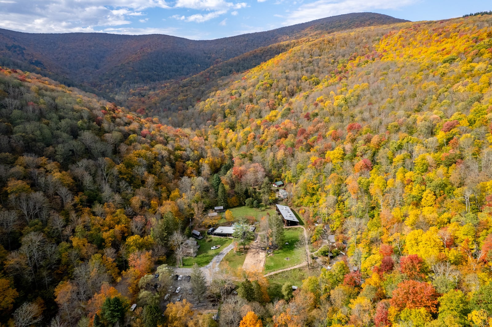 Aerial view of Eastwind Oliverea Valley surrounded by forested mountains.