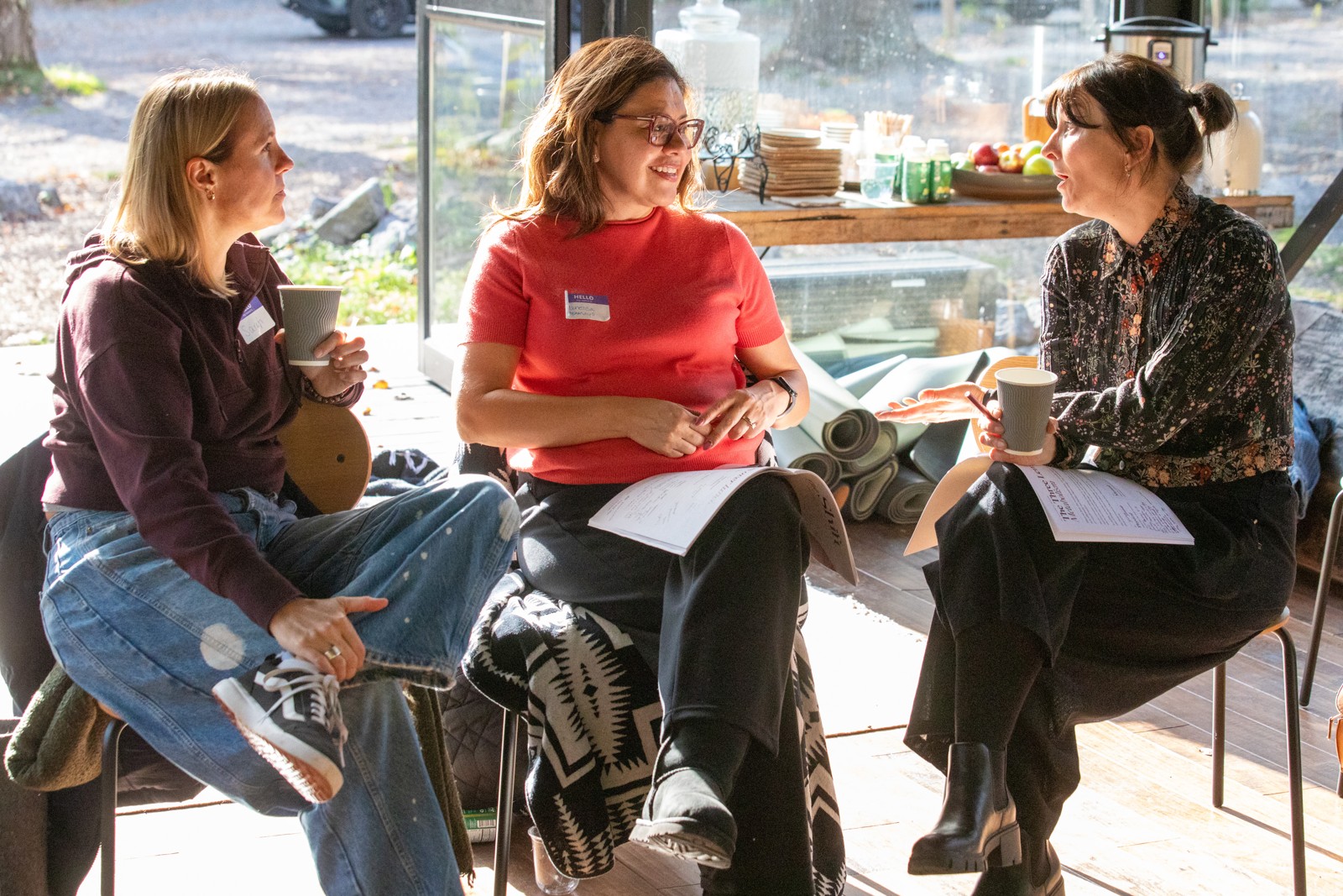 Three participants sharing a conversation with notebooks and mugs at The Shift